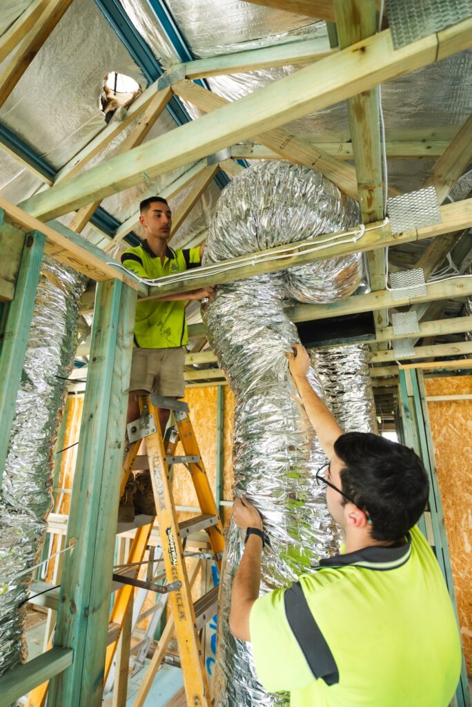 Amped Up Air technicians installing flexible ductwork in a ceiling space