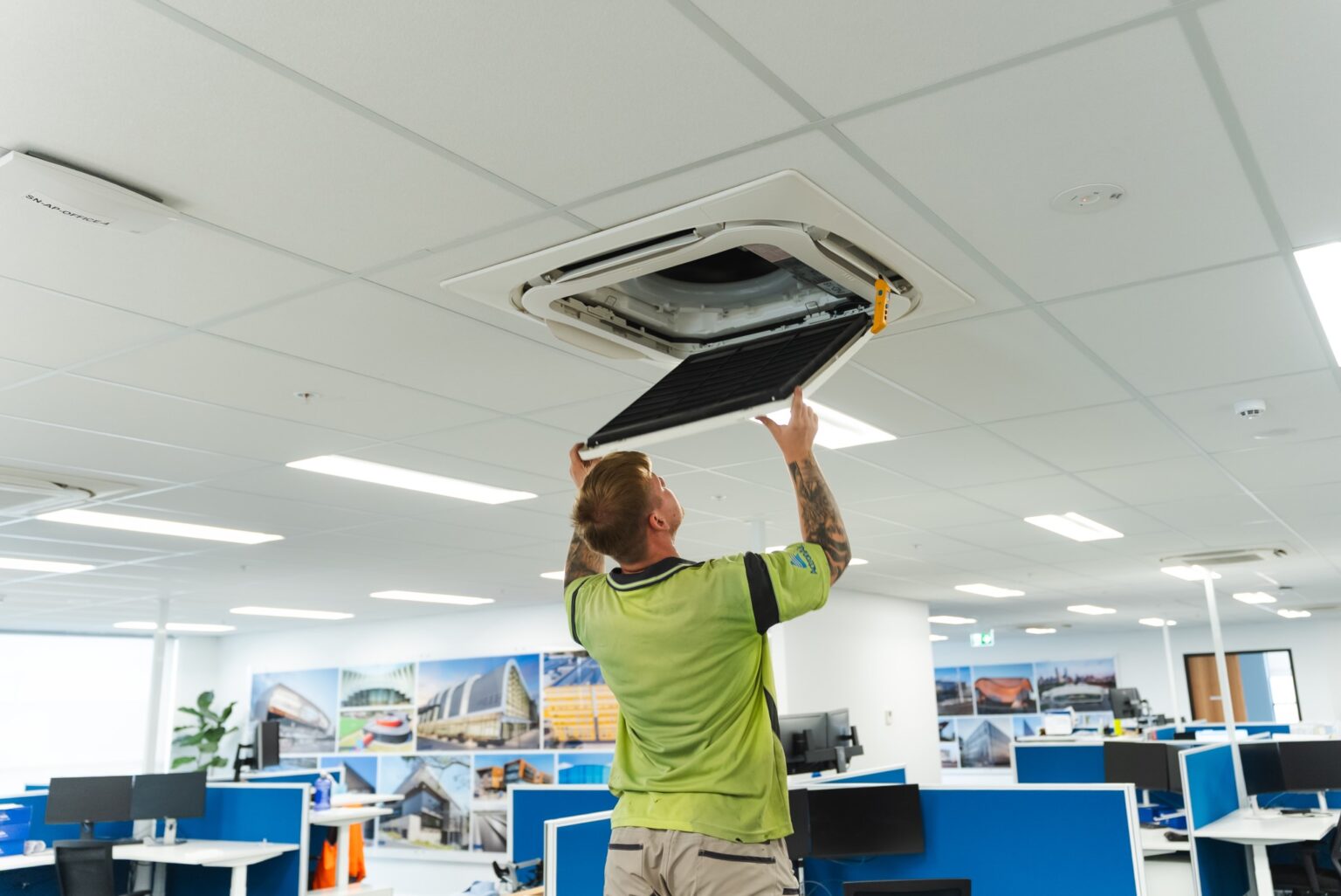 Technician removing a filter from a ceiling-mounted commercial air conditioner